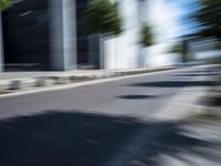 the skateboarder is going down the road in the blurry photo, which appears to be in motion