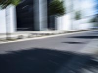 the skateboarder is going down the road in the blurry photo, which appears to be in motion