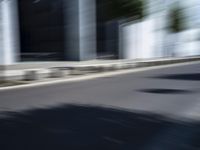 the skateboarder is going down the road in the blurry photo, which appears to be in motion