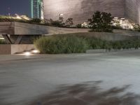 a man rides his skateboard on a street in front of a large, modern building