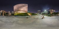 a skateboarder is doing tricks on a half pipe at night time in front of a building with a circular dome in the back ground