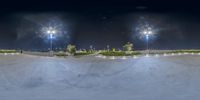 a skateboarder performs tricks at night on a slope outside a skate park at night