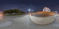 a skateboarder performing a trick on a ramp at night time near a building