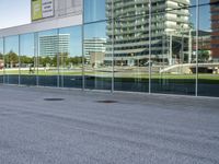 a skateboarder riding past an office building with large windows on either side of it