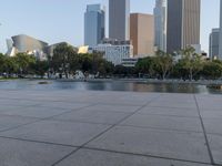 a skateboarder on a cement surface overlooking the water and tall buildings in a city