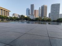 a skateboarder on a cement surface overlooking the water and tall buildings in a city