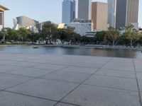 a skateboarder on a cement surface overlooking the water and tall buildings in a city