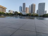 a skateboarder on a cement surface overlooking the water and tall buildings in a city