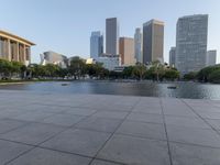 a skateboarder on a cement surface overlooking the water and tall buildings in a city