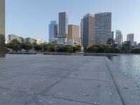 a skateboarder on a cement surface overlooking the water and tall buildings in a city