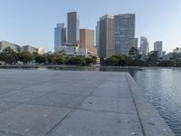 a skateboarder on a cement surface overlooking the water and tall buildings in a city