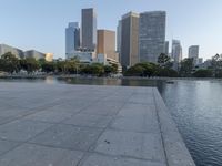 a skateboarder on a cement surface overlooking the water and tall buildings in a city