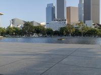 a skateboarder on a cement surface overlooking the water and tall buildings in a city