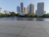 a skateboarder on a cement surface overlooking the water and tall buildings in a city