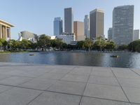 a skateboarder on a cement surface overlooking the water and tall buildings in a city