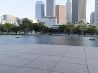 a skateboarder on a cement surface overlooking the water and tall buildings in a city