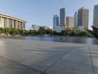 a skateboarder on a cement surface overlooking the water and tall buildings in a city