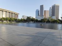 a skateboarder on a cement surface overlooking the water and tall buildings in a city