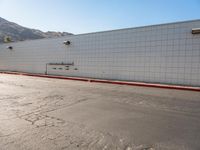 a skateboarder is riding down a cement street in a white tiled building area