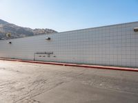 a skateboarder is riding down a cement street in a white tiled building area