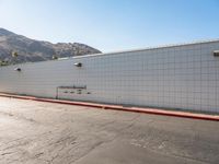 a skateboarder is riding down a cement street in a white tiled building area