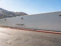 a skateboarder is riding down a cement street in a white tiled building area