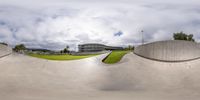 a skateboarder doing tricks at a park on a cloudy day, near a building