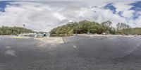 a skateboarder doing tricks at a parking lot near trees with boats in background