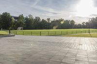 a skateboarder performs a trick on an empty brick area at the edge of a tennis court