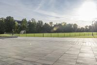 a skateboarder performs a trick on an empty brick area at the edge of a tennis court