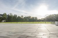 a skateboarder performs a trick on an empty brick area at the edge of a tennis court