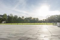 a skateboarder performs a trick on an empty brick area at the edge of a tennis court