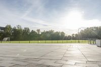 a skateboarder performs a trick on an empty brick area at the edge of a tennis court