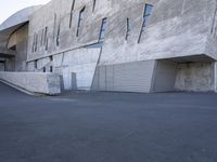 skateboarder going down the ramp of an industrial building in the daytime with clear windows