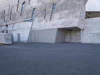 skateboarder going down the ramp of an industrial building in the daytime with clear windows