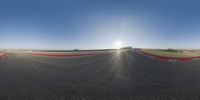 a skateboarder rides on a ramp in the middle of a race track, with the sun shining