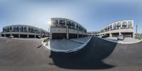 a view from the bottom of a skateboarder on the ramp in a street with parking spaces