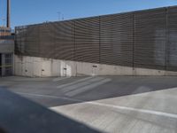 a skateboarder on a ramp looking back at an exit gate in a parking lot