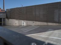 a skateboarder on a ramp looking back at an exit gate in a parking lot