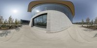 a skateboarder rides down a half pipe that sits outside of an architectured building