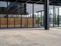 a skateboarder rides his board on the sidewalk outside an office building with windows