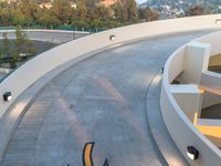 a skateboarder rides on the ramp in a curve shaped ramp between two large buildings and a mountain in the background