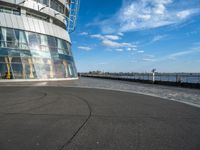 a skateboarder riding through a curved walkway near the ocean with a building on top