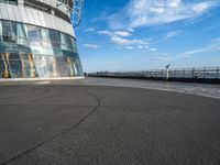 a skateboarder riding through a curved walkway near the ocean with a building on top