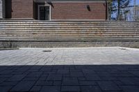 a skateboarder riding down a stone brick patio with stairs leading to a building