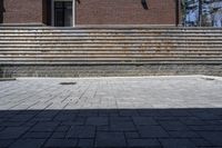 a skateboarder riding down a stone brick patio with stairs leading to a building