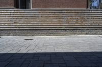 a skateboarder riding down a stone brick patio with stairs leading to a building