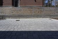 a skateboarder riding down a stone brick patio with stairs leading to a building