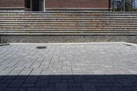 a skateboarder riding down a stone brick patio with stairs leading to a building