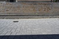 a skateboarder riding down a stone brick patio with stairs leading to a building